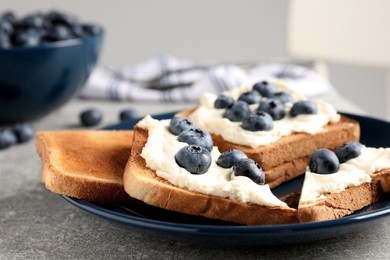 Photo of Tasty sandwiches with cream cheese and blueberries on grey table, closeup