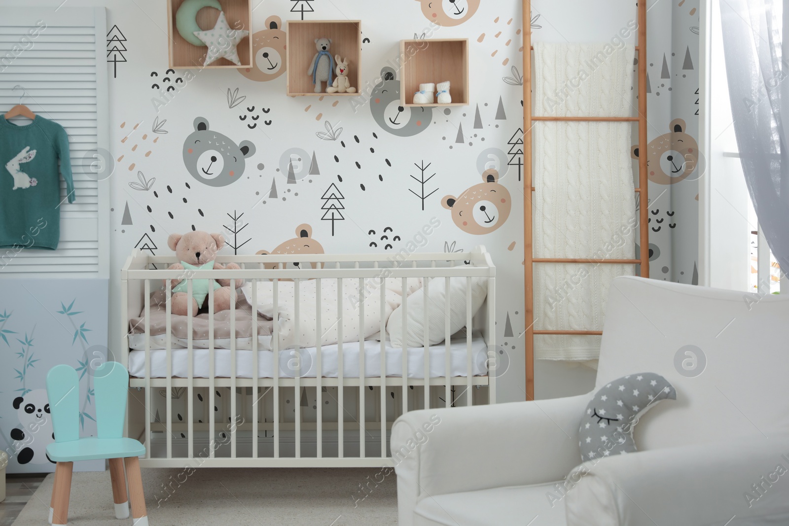 Image of Stylish baby room interior with crib, armchair and cute wallpapers