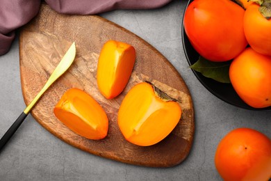 Delicious ripe persimmons and knife on light gray table, flat lay