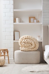 Photo of Soft chunky knit blanket and pouf in stylish room interior