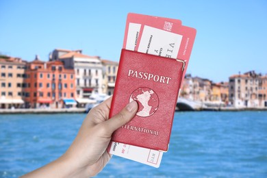 Image of Woman holding international passport with boarding passes and beautiful view of city near sea on background