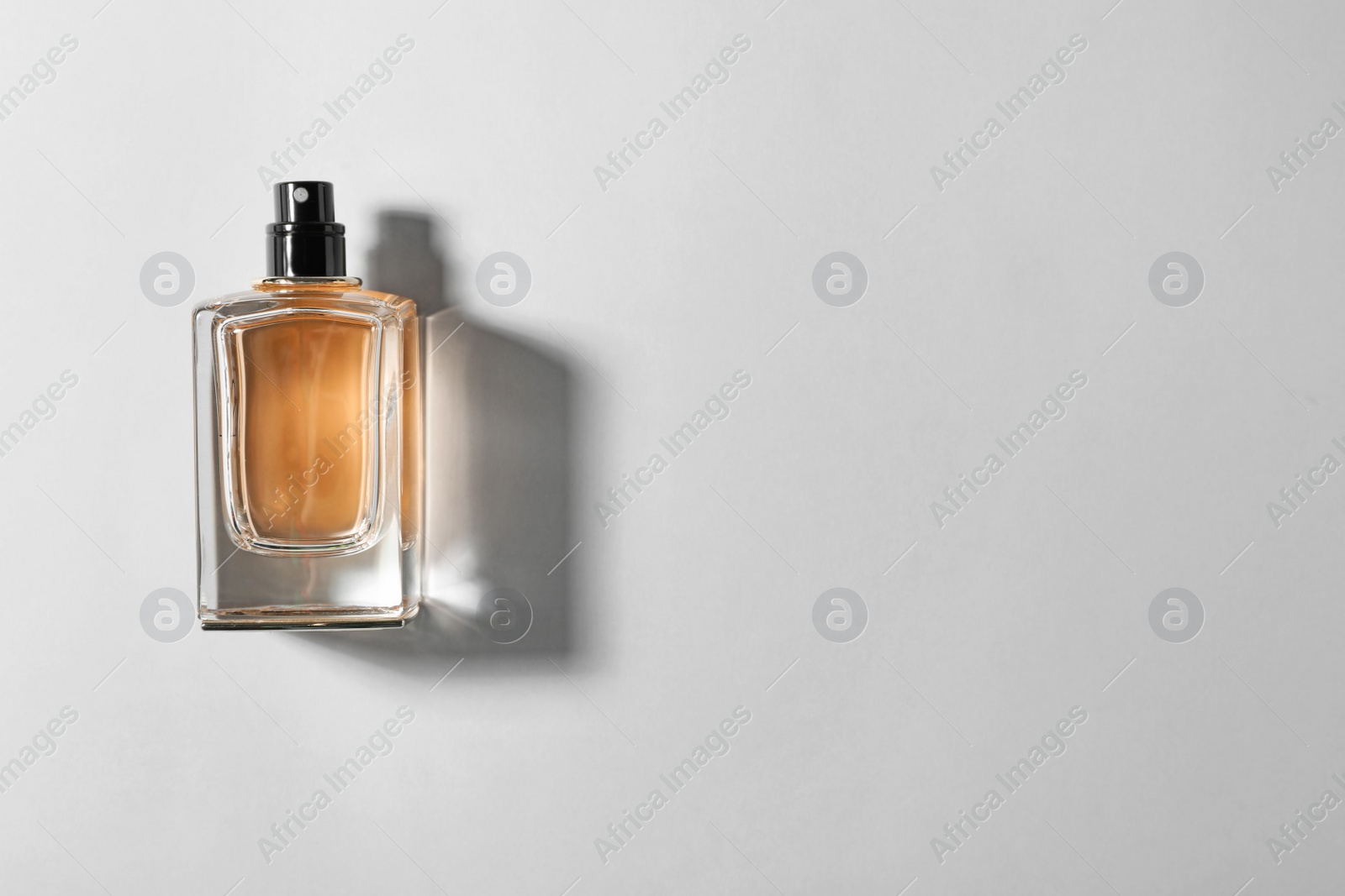 Photo of Bottle of perfume on light background, top view