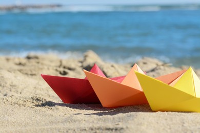 Photo of Three paper boats near sea on sunny day, closeup