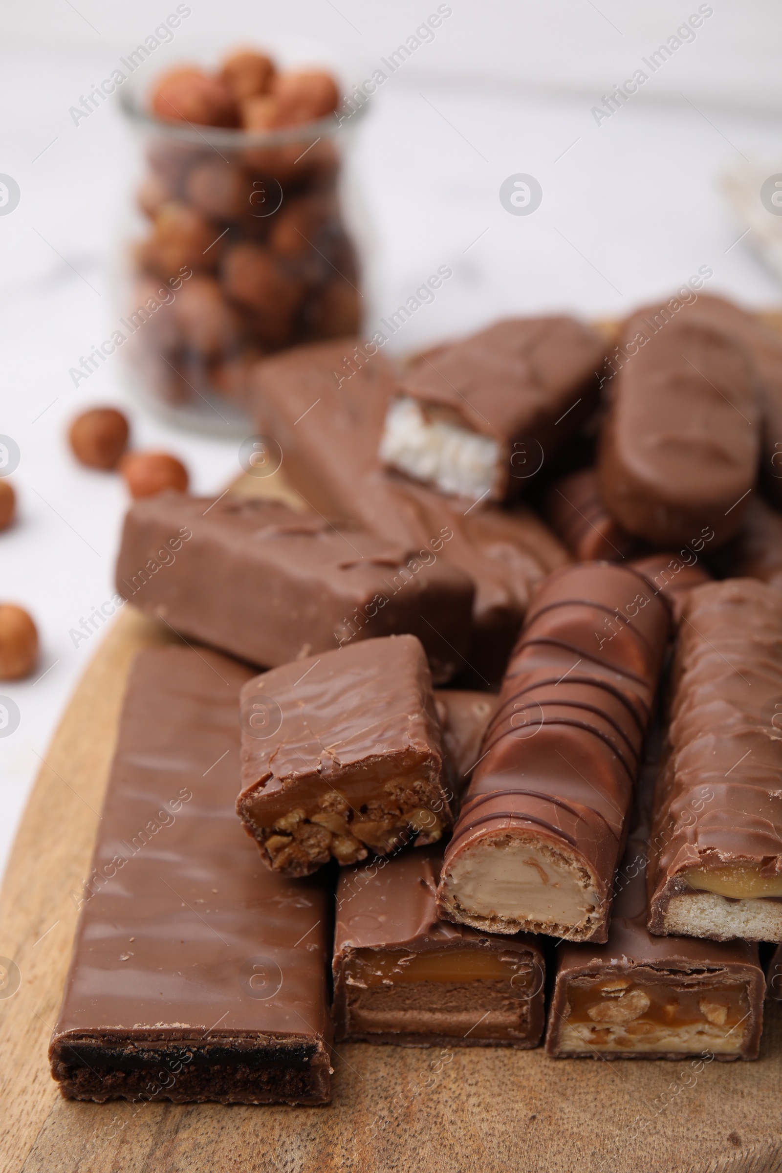 Photo of Pieces of different tasty chocolate bars on wooden board, closeup