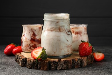 Tasty yoghurt with jam and strawberries on grey textured table, closeup