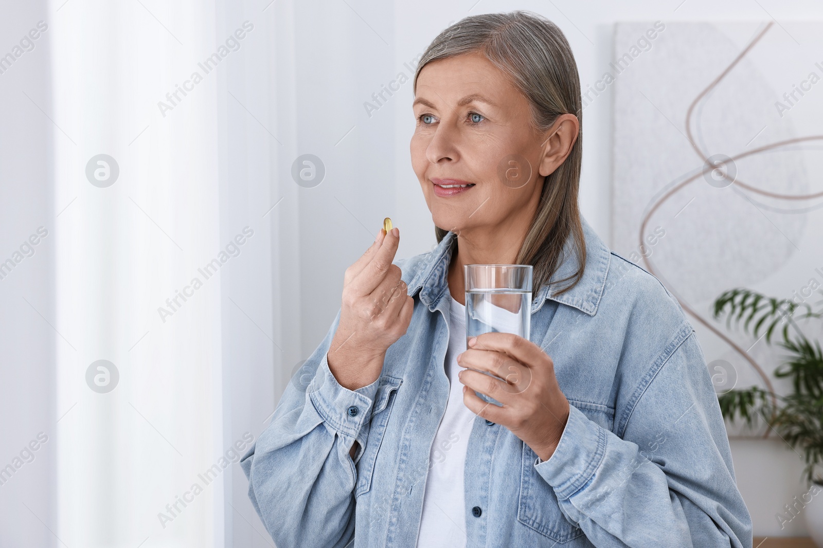 Photo of Beautiful woman taking vitamin pill at home