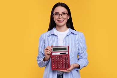 Smiling accountant with calculator on yellow background