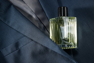 Photo of Luxury men's perfume in bottle on grey jacket, top view. Space for text