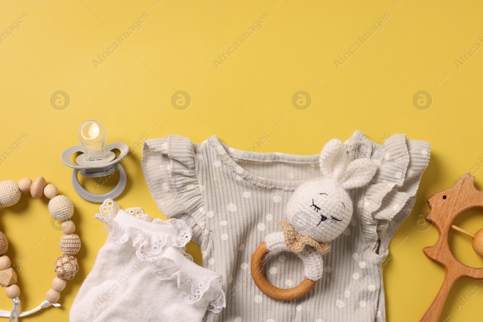 Photo of Different baby accessories on yellow background, flat lay. Space for text