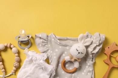 Different baby accessories on yellow background, flat lay. Space for text