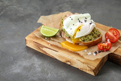 Photo of Delicious sandwich with guacamole, shrimps and fried egg on grey table, closeup
