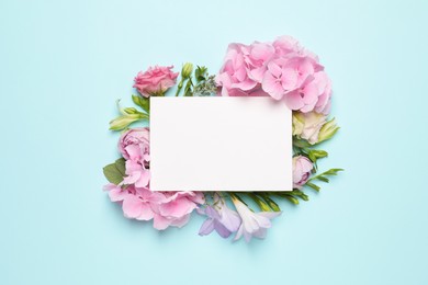 Beautiful composition with hortensia flowers and blank card on light blue background, top view. Space for text