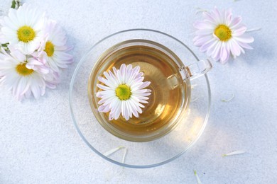 Photo of Glass cup of delicious chamomile tea on white table, top view