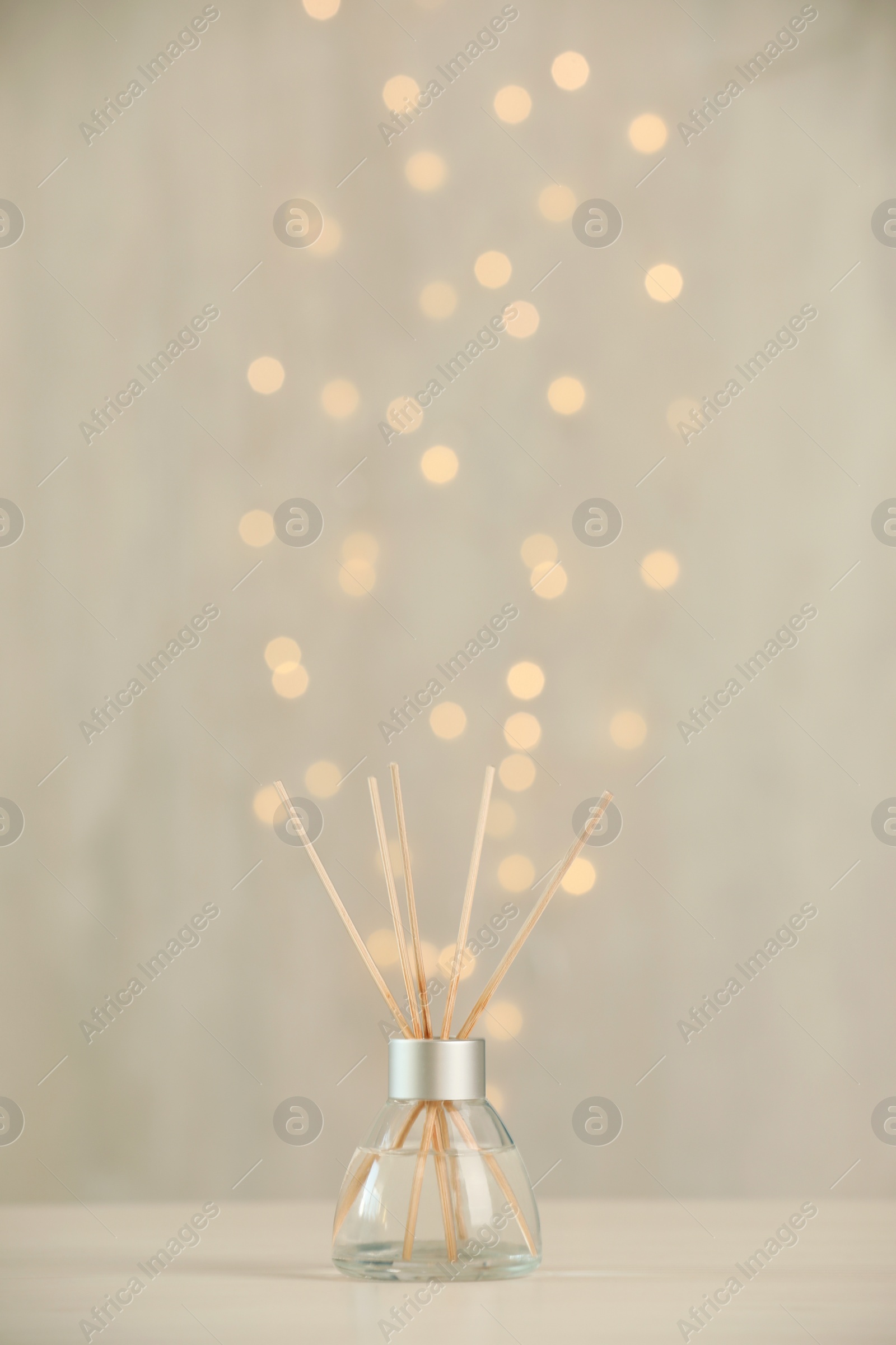 Photo of Aromatic reed air freshener on light table against blurred lights