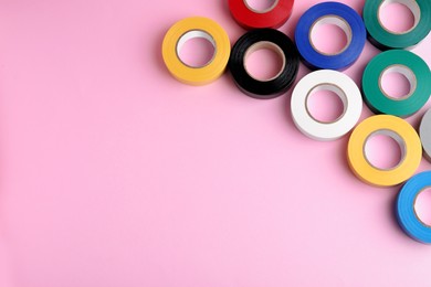 Photo of Colorful insulating tapes on pink background, flat lay. Space for text