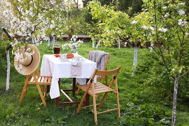 Stylish table setting with beautiful spring flowers, tea and croissants in garden