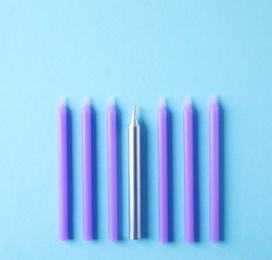 Bright birthday candles on light blue background, flat lay