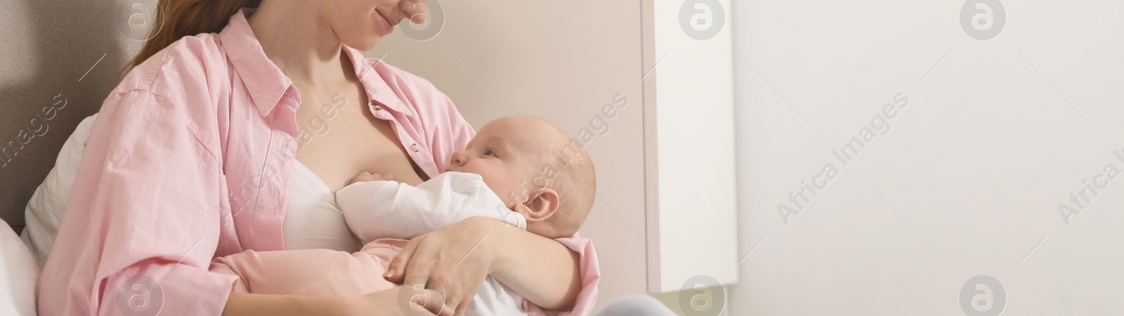 Image of Young woman breast feeding her little baby at home, space for text. Banner design