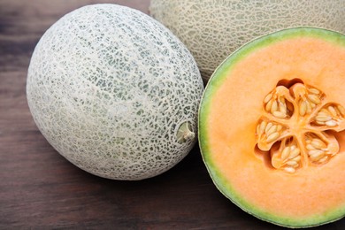 Photo of Whole and cut fresh ripe melons on wooden table, closeup