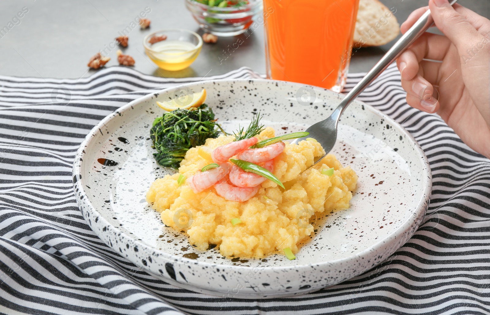 Photo of Woman eating fresh tasty shrimp and grits at table