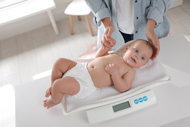 Photo of Young woman weighting her cute baby at home, above view. Health care