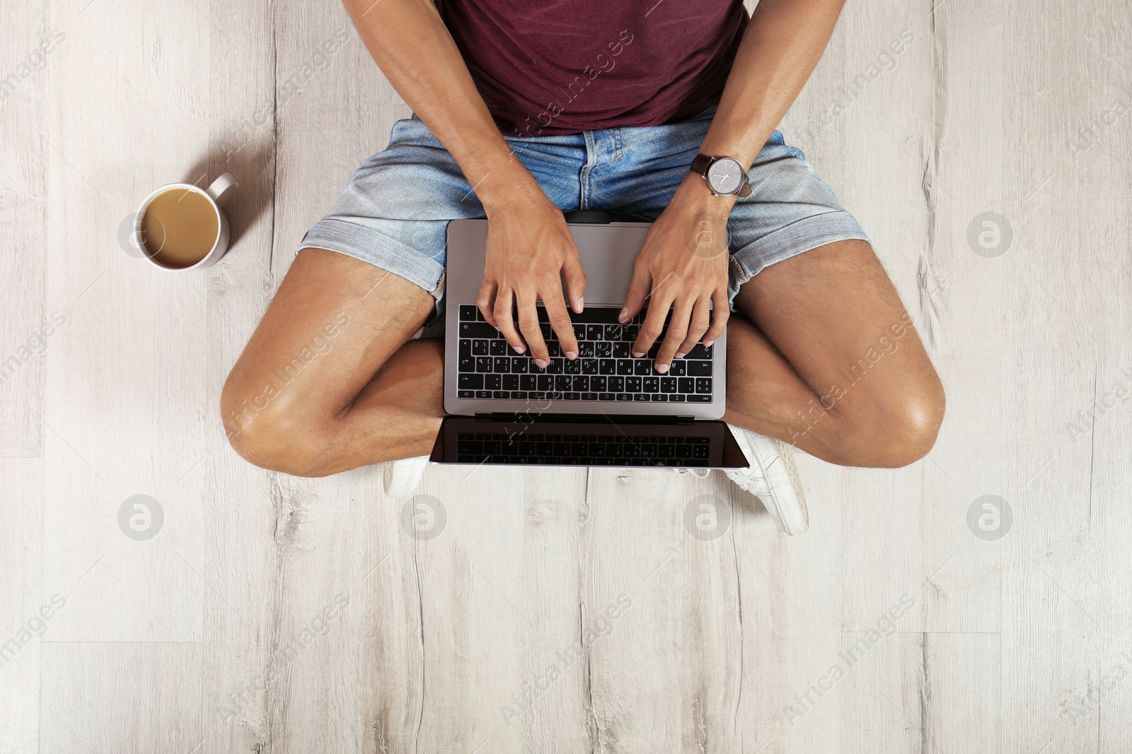 Photo of Young man with laptop sitting on floor, top view