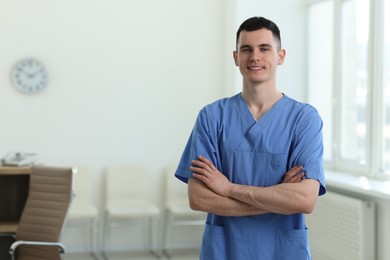 Photo of Portrait of smiling medical assistant with crossed arms in hospital. Space for text