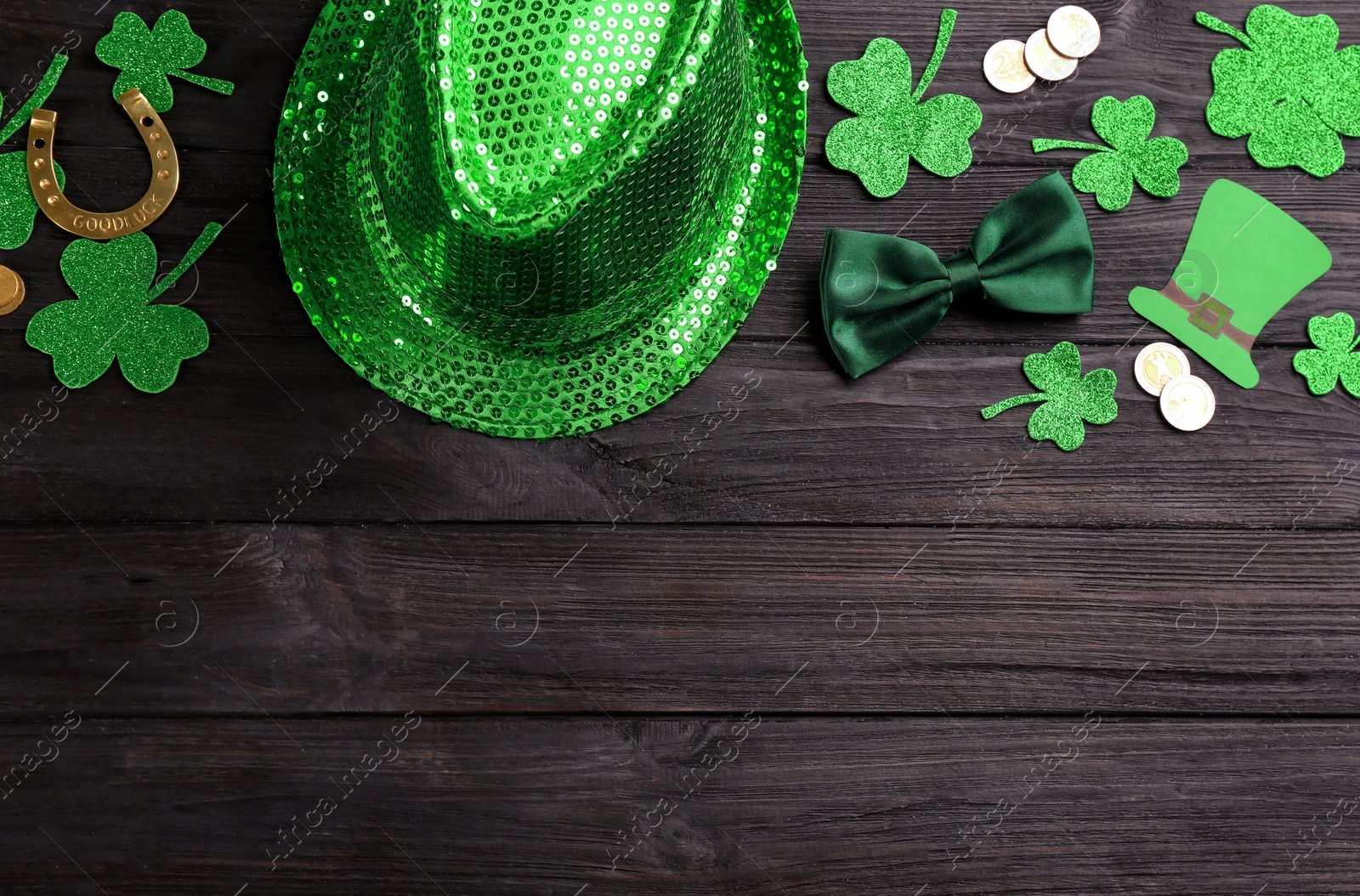 Photo of Leprechaun's hat and St. Patrick's day decor on black wooden background, flat lay. Space for text