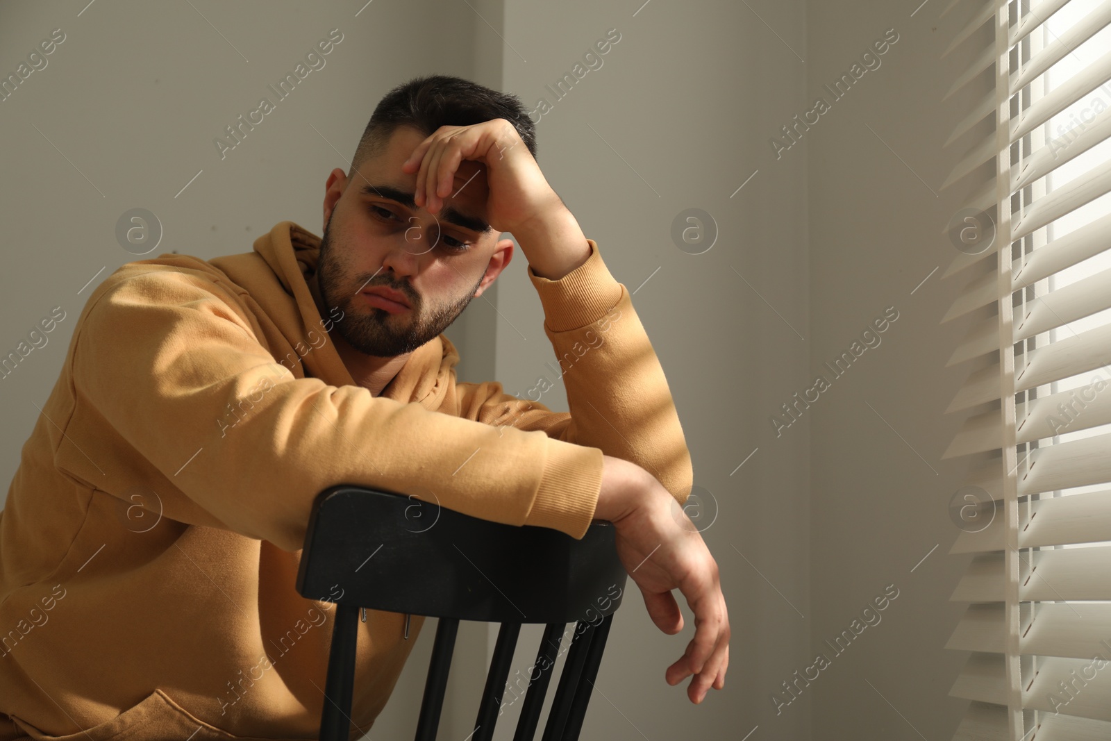 Photo of Sad man sitting on chair near window. Space for text