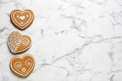 Photo of Tasty heart shaped gingerbread cookies on white marble table, flat lay. Space for text