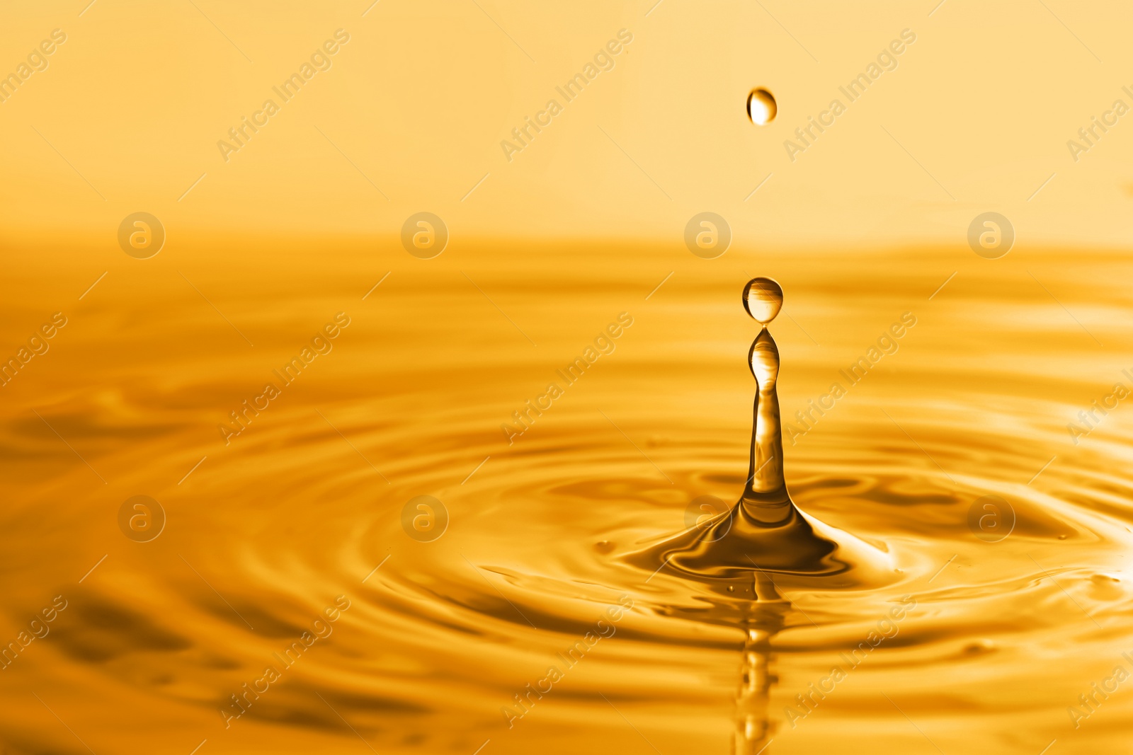 Image of Splash of golden oily liquid with drops as background, closeup