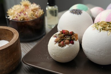 Photo of Plate with different bath bombs on wooden table, closeup