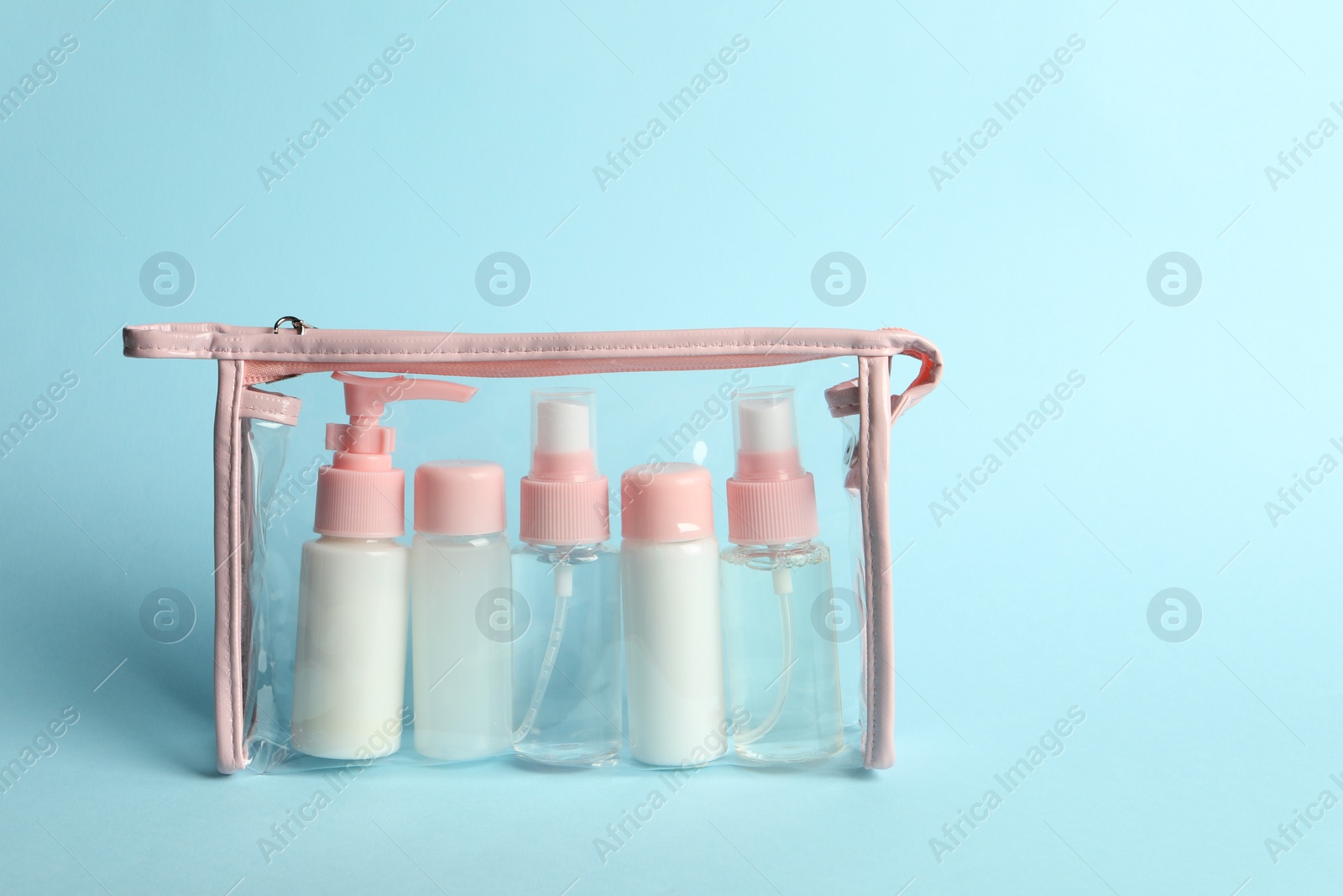 Photo of Cosmetic travel kit in plastic bag on light blue background. Space for text