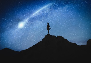 Image of Silhouette of woman in mountains under starry sky at night