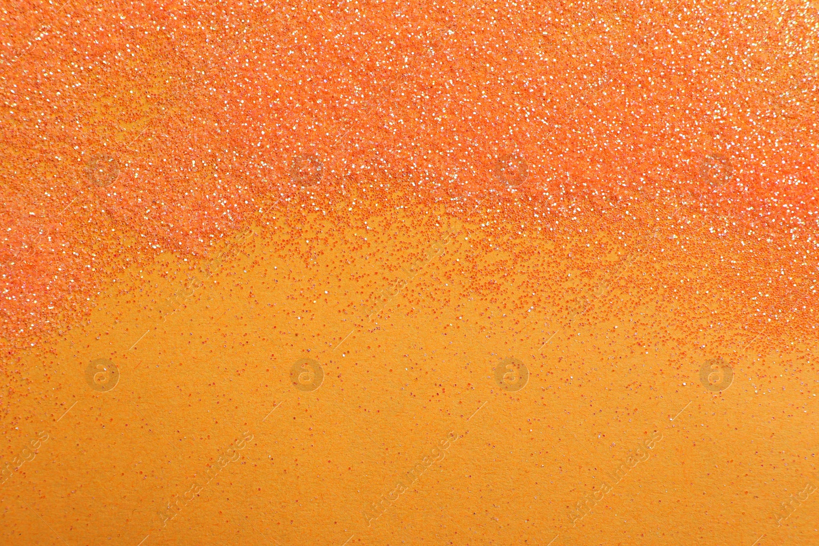 Photo of Shiny bright glitter on orange background, flat lay. Space for text