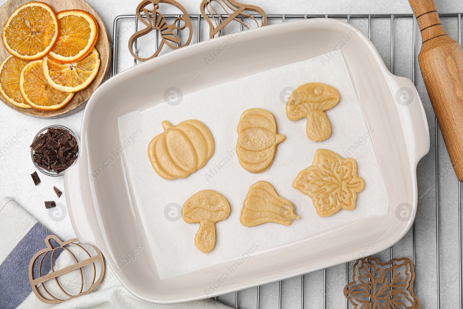 Photo of Home baking. Flat lay composition with uncooked biscuits of different shapes and cookie cutters on light table