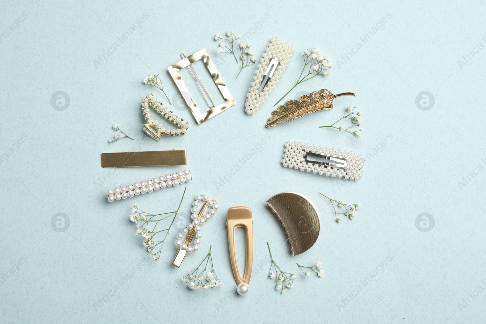 Photo of Frame of stylish hair clips and flowers on light background, flat lay