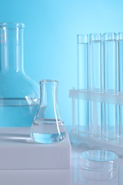 Laboratory analysis. Glass test tubes and flasks on table against light blue background