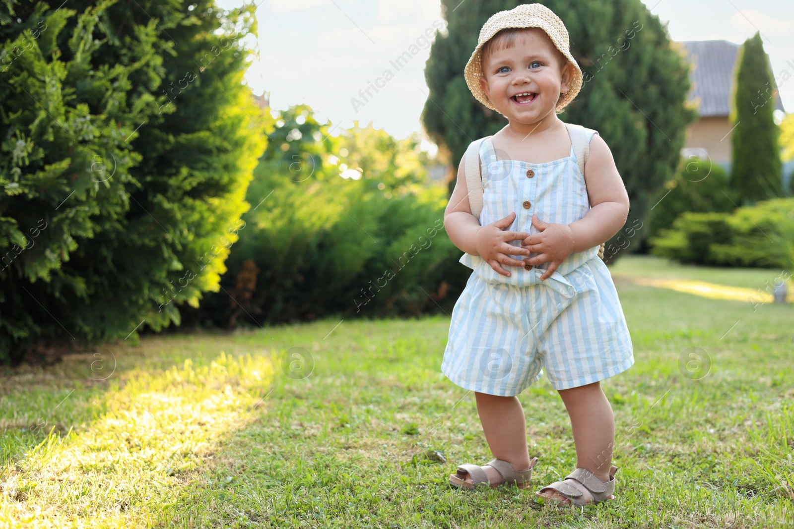 Photo of Cute little girl wearing stylish clothes outdoors on sunny day. Space for text