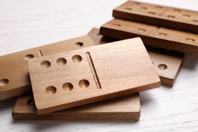 Photo of Wooden domino tiles on white table, closeup
