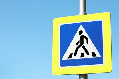 Photo of Post with Pedestrian Crossing traffic sign against blue sky on sunny day. Space for text
