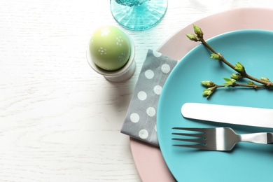 Photo of Festive Easter table setting with painted egg on wooden background, top view. Space for text