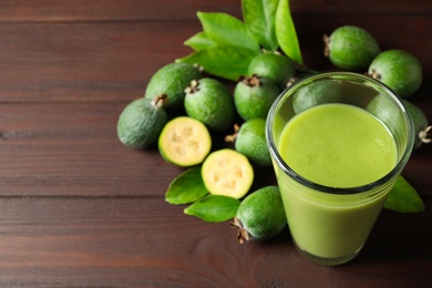 Fresh feijoa smoothie in glass on wooden table, closeup. Space for text