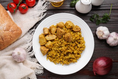 Delicious rice with chicken served on wooden table, flat lay