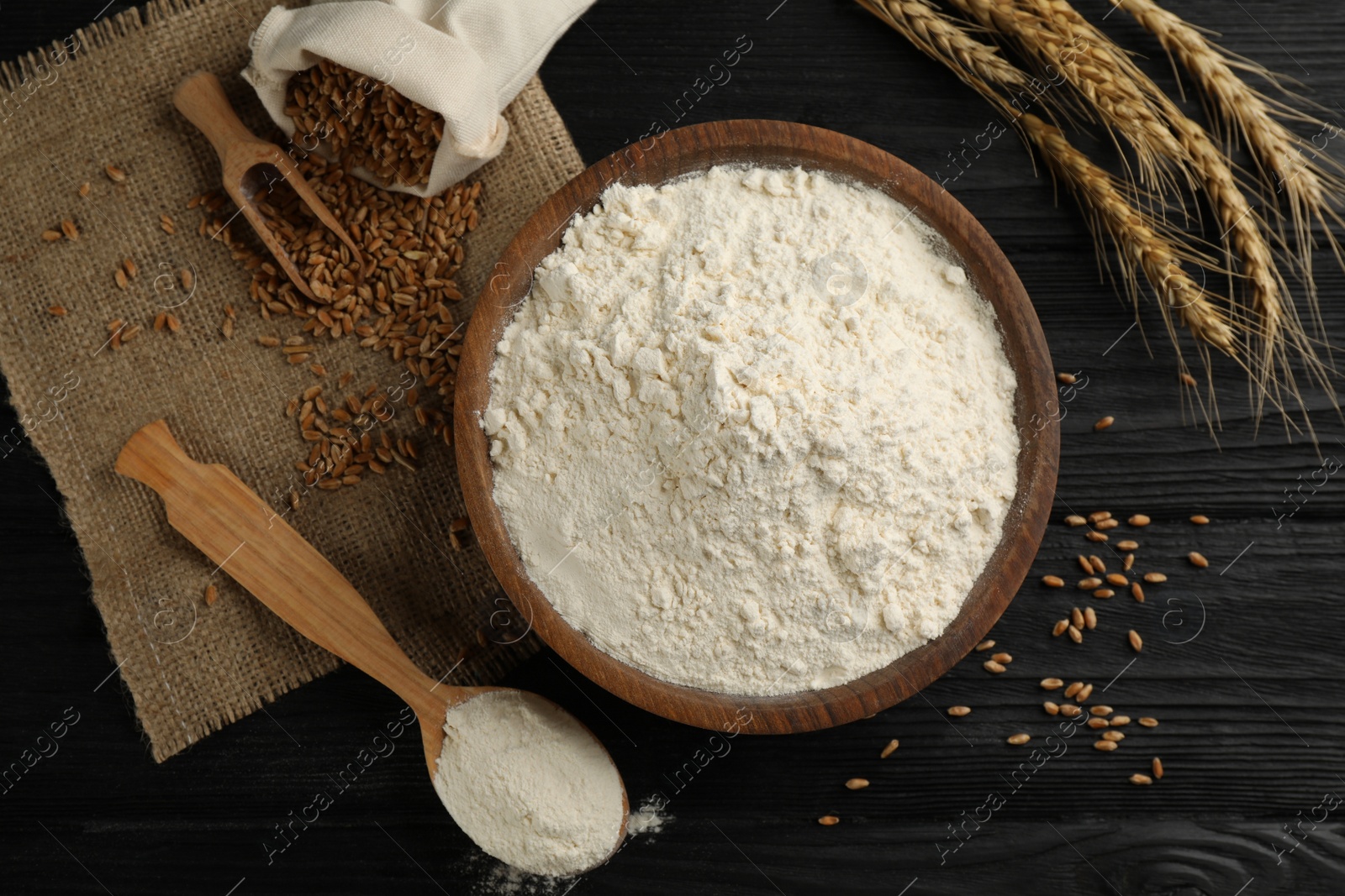 Photo of Flat lay composition with wheat flour on black wooden table