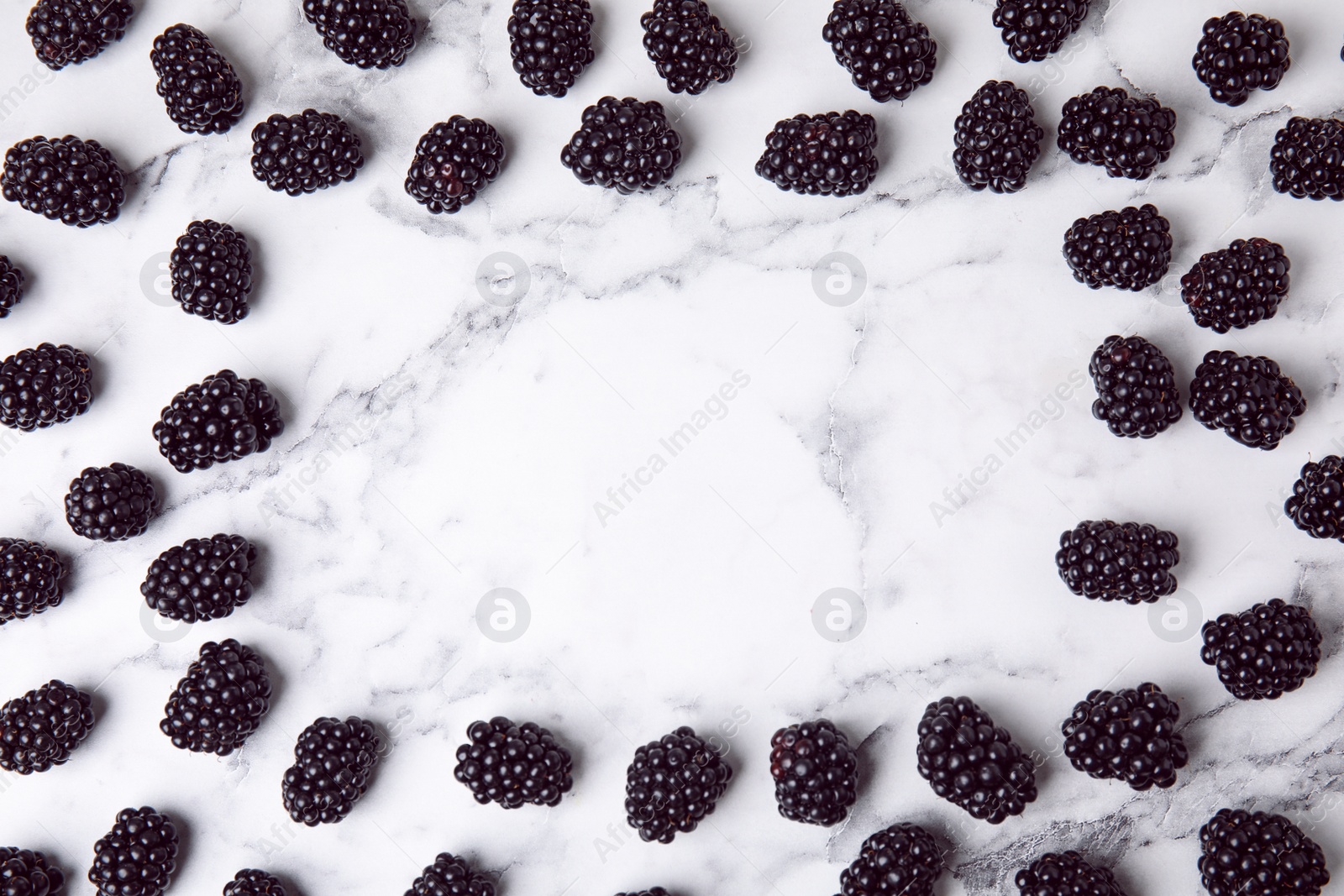 Photo of Frame made of tasty blackberries on marble table, top view with space for text