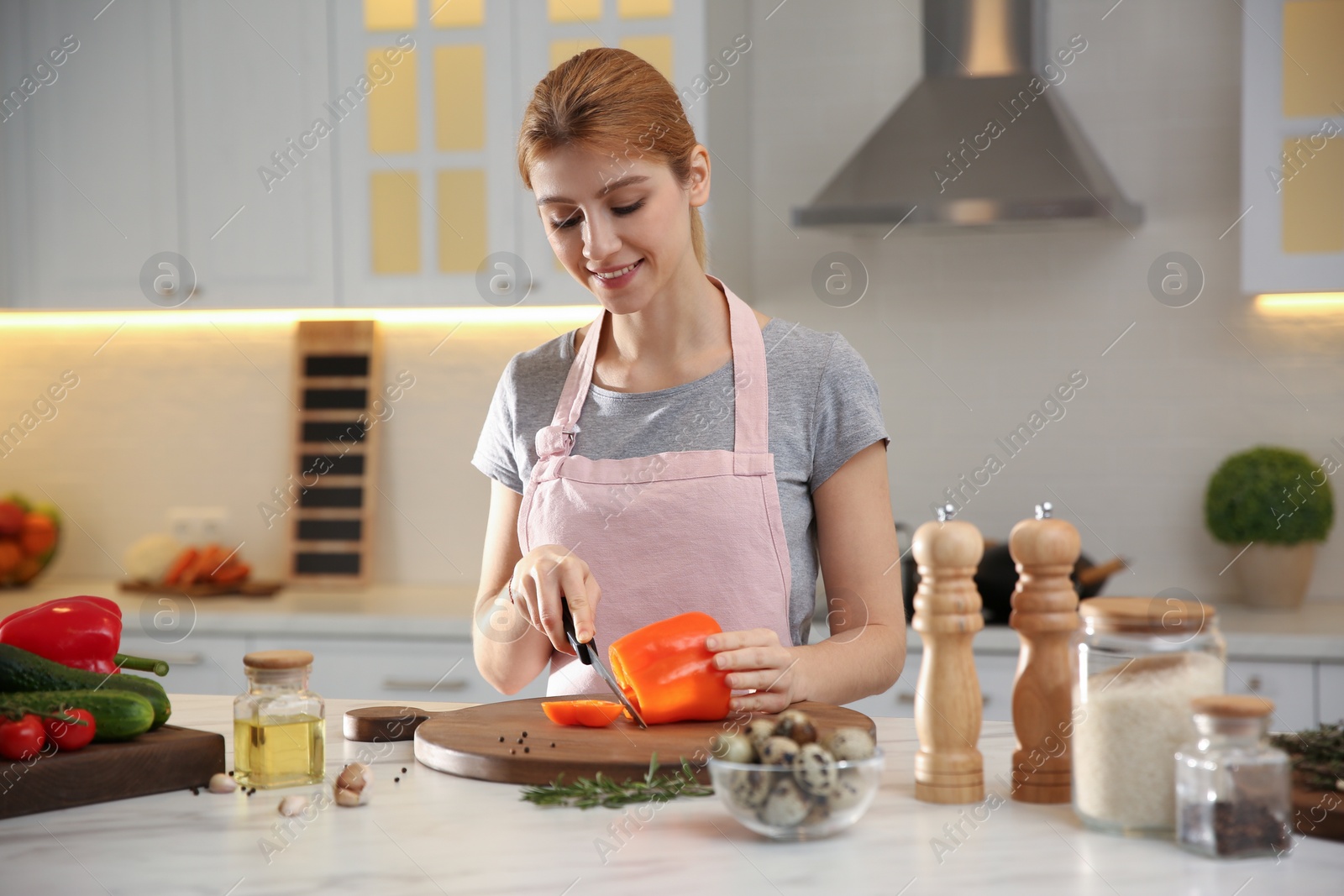 Photo of Young woman cooking at table in kitchen