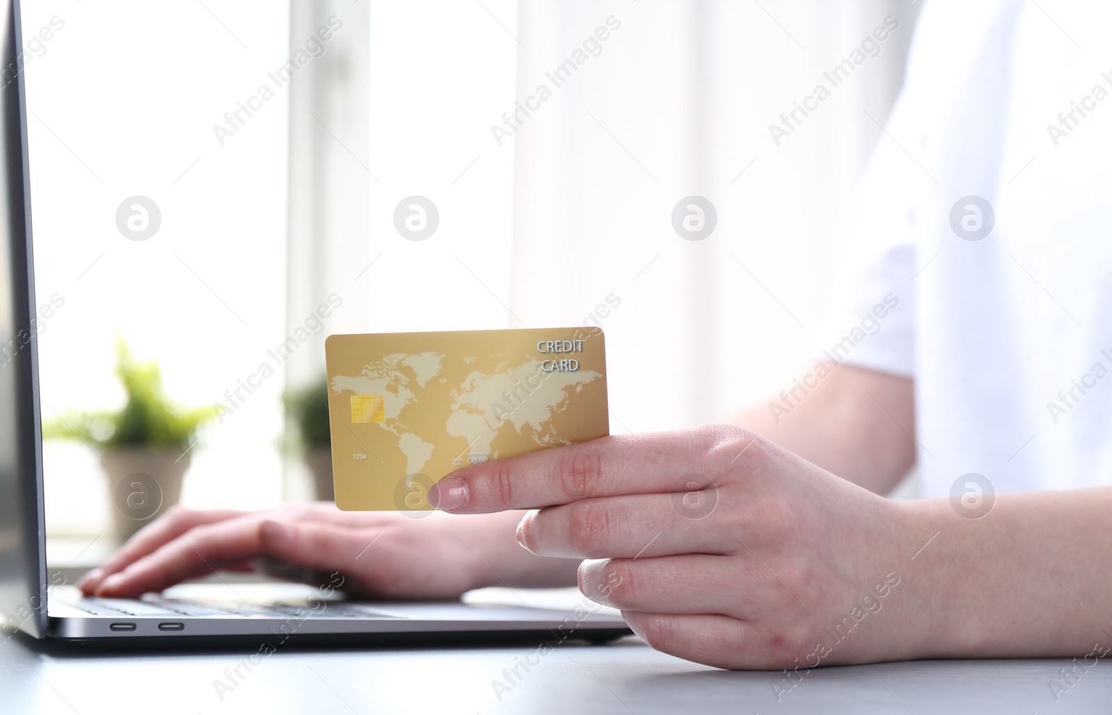 Photo of Online payment. Woman with laptop and credit card at white table, closeup