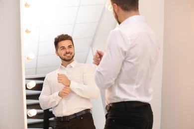 Young man looking at himself in large mirror at home