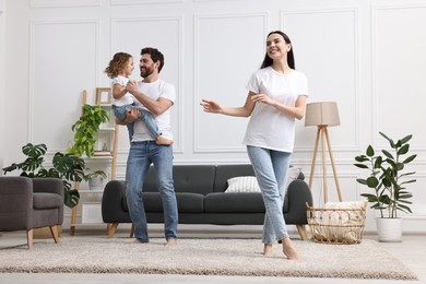 Photo of Happy family dancing and having fun in living room, low angle view